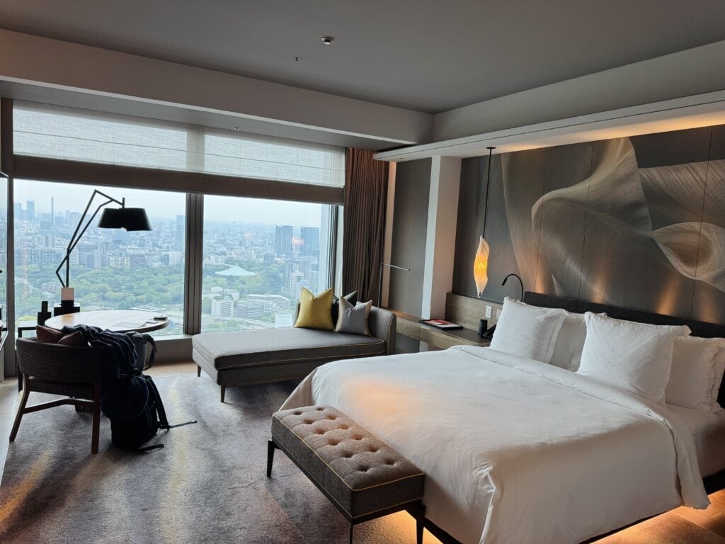 Hotel room with bed and a view of Tokyo city.
