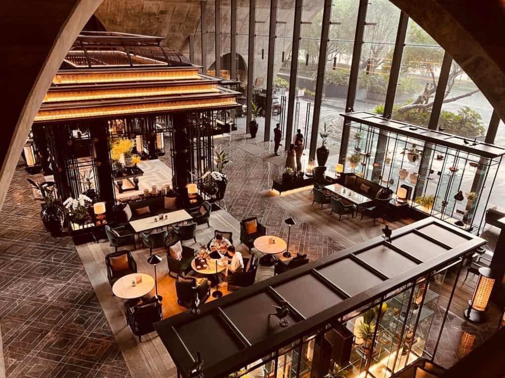 An overview photo of the lobby of Sindhorn Kempinski Bangkok, featuring designer furniture and warm lighting.