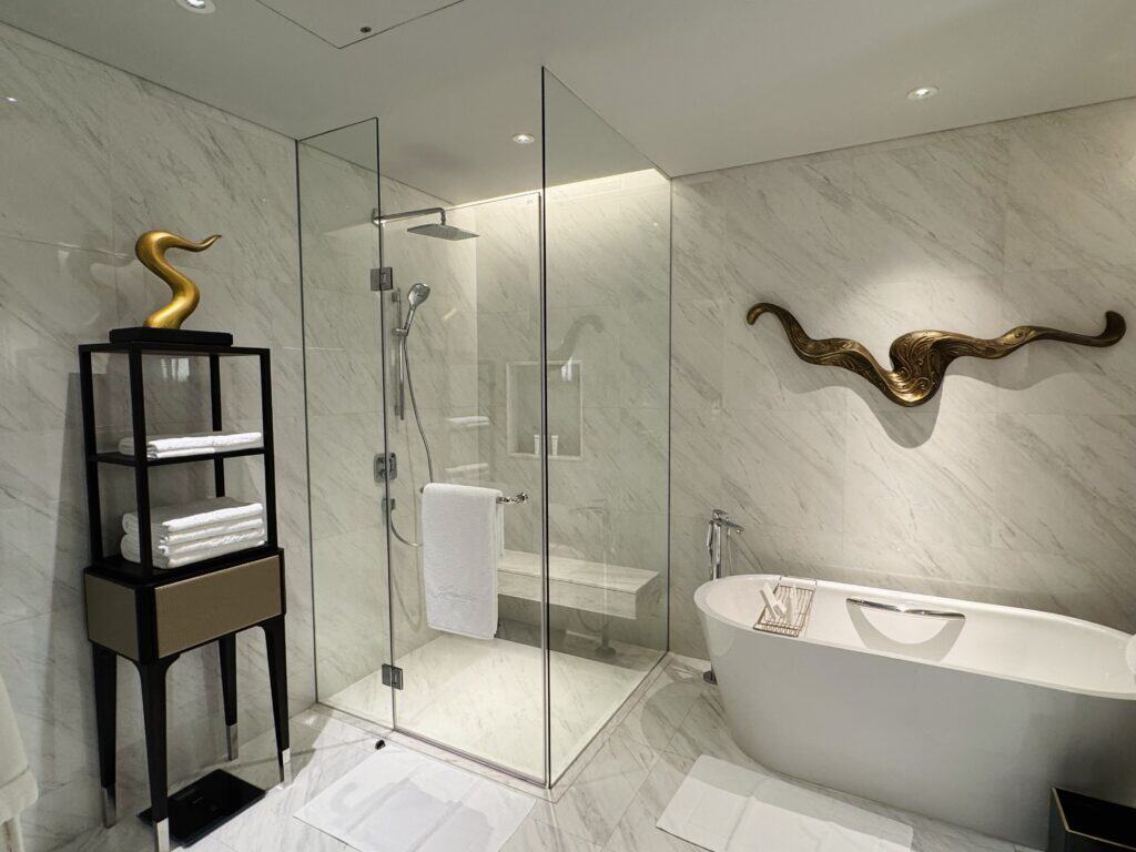 Luxurious bathroom with freestanding bath and gold sculpture at Sindhorn Kempinski Bangkok.