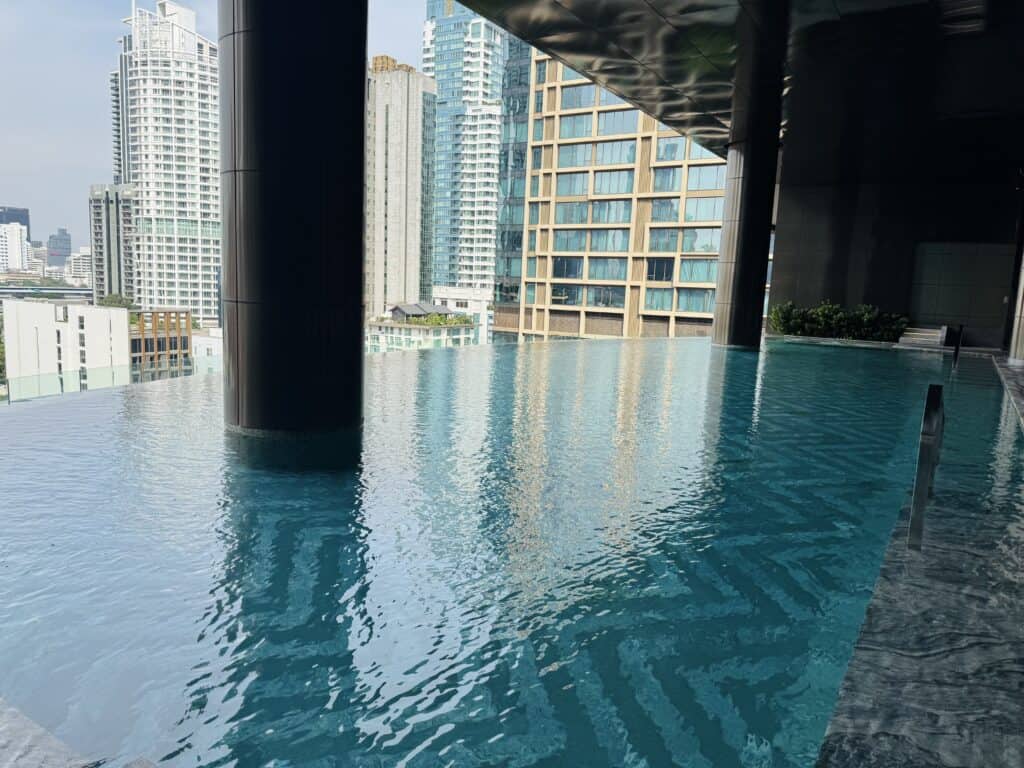 Infinity pool at Sindhorn Kempinski Bangkok with a view of the Bangkok skyline during the day.
