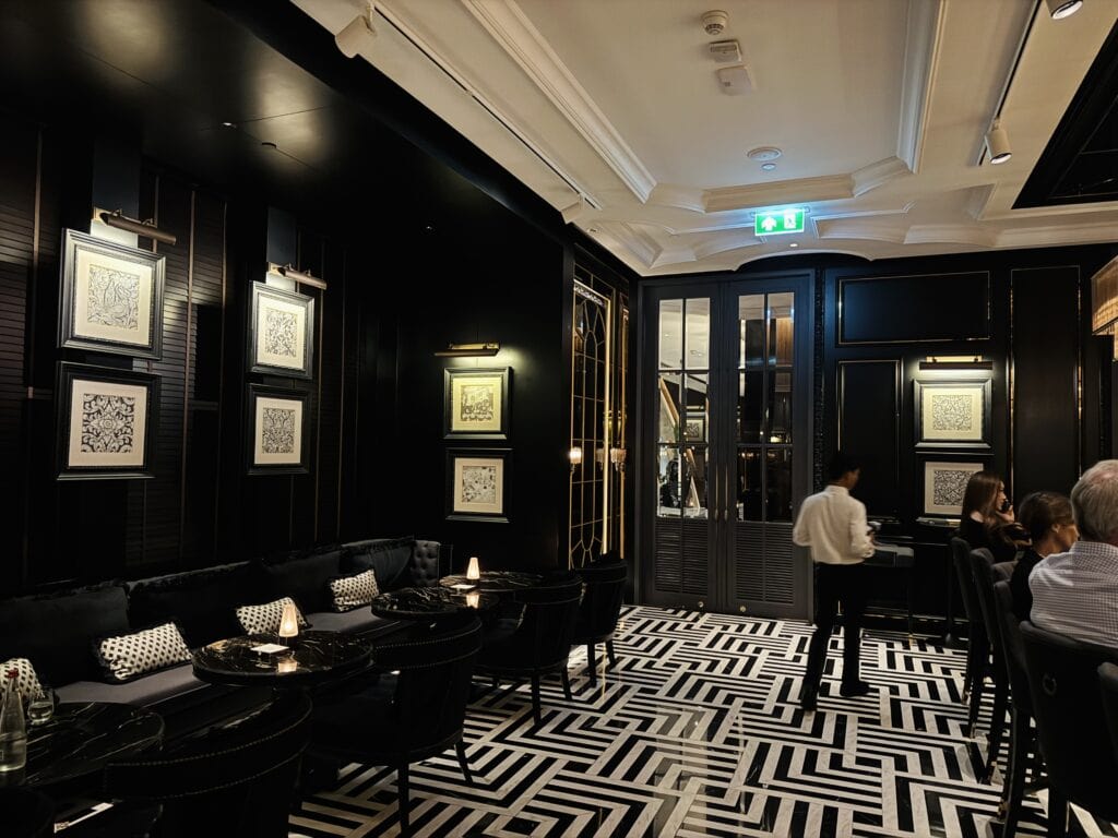 Lounge of the Firefly Bar at Sindhorn Kempinski Bangkok with black walls and a graphic black and white floor.