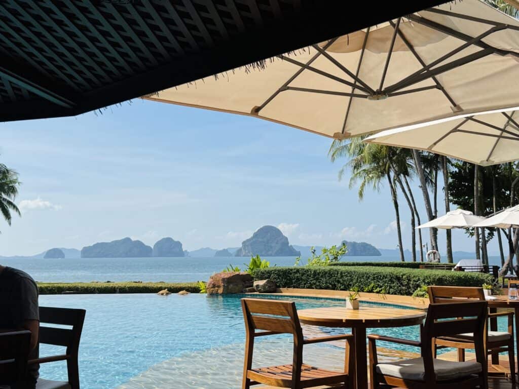 Terrace with wooden tables at the infinity pool of Phulay Bay overlooking the Hong Islands in Krabi.