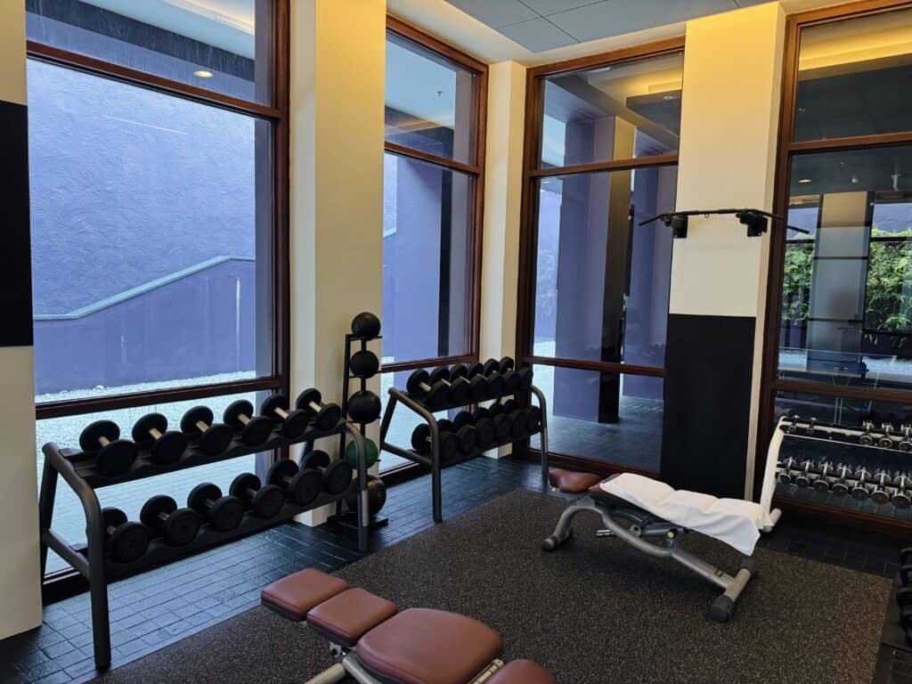 Phulay Bay's modern fitness centre features dumbbells, a workout bench and large windows.