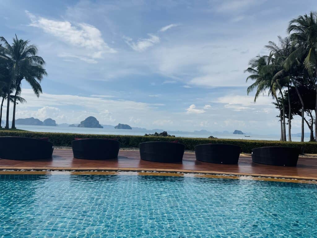 Loungers in front of Phulay Bay's infinity pool overlooking the Andaman Sea and rock formations.