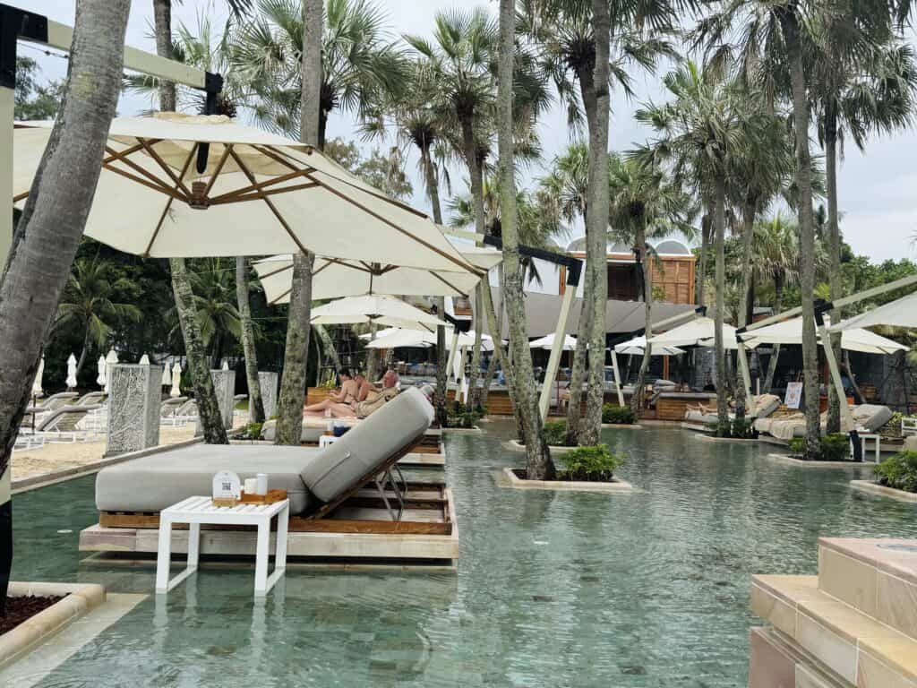 Lagoon pool at Anantara Mai Khao Phuket with daybeds among palm trees.