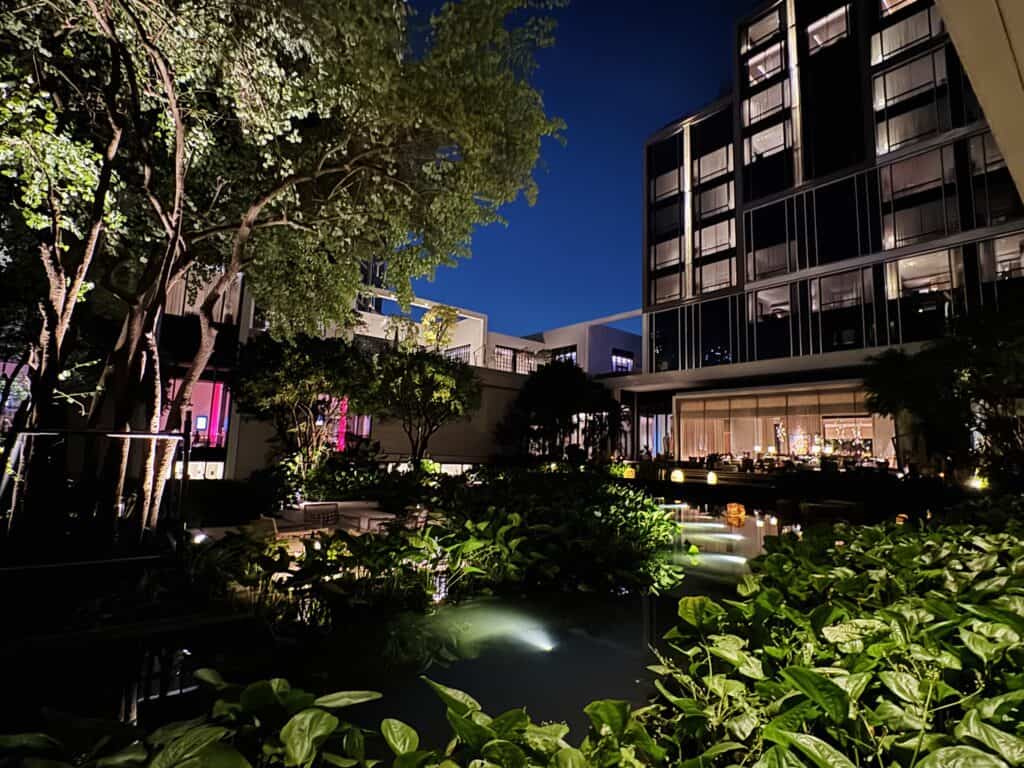 Tropical courtyard of Four Seasons Bangkok in the evening with water features and modern architecture